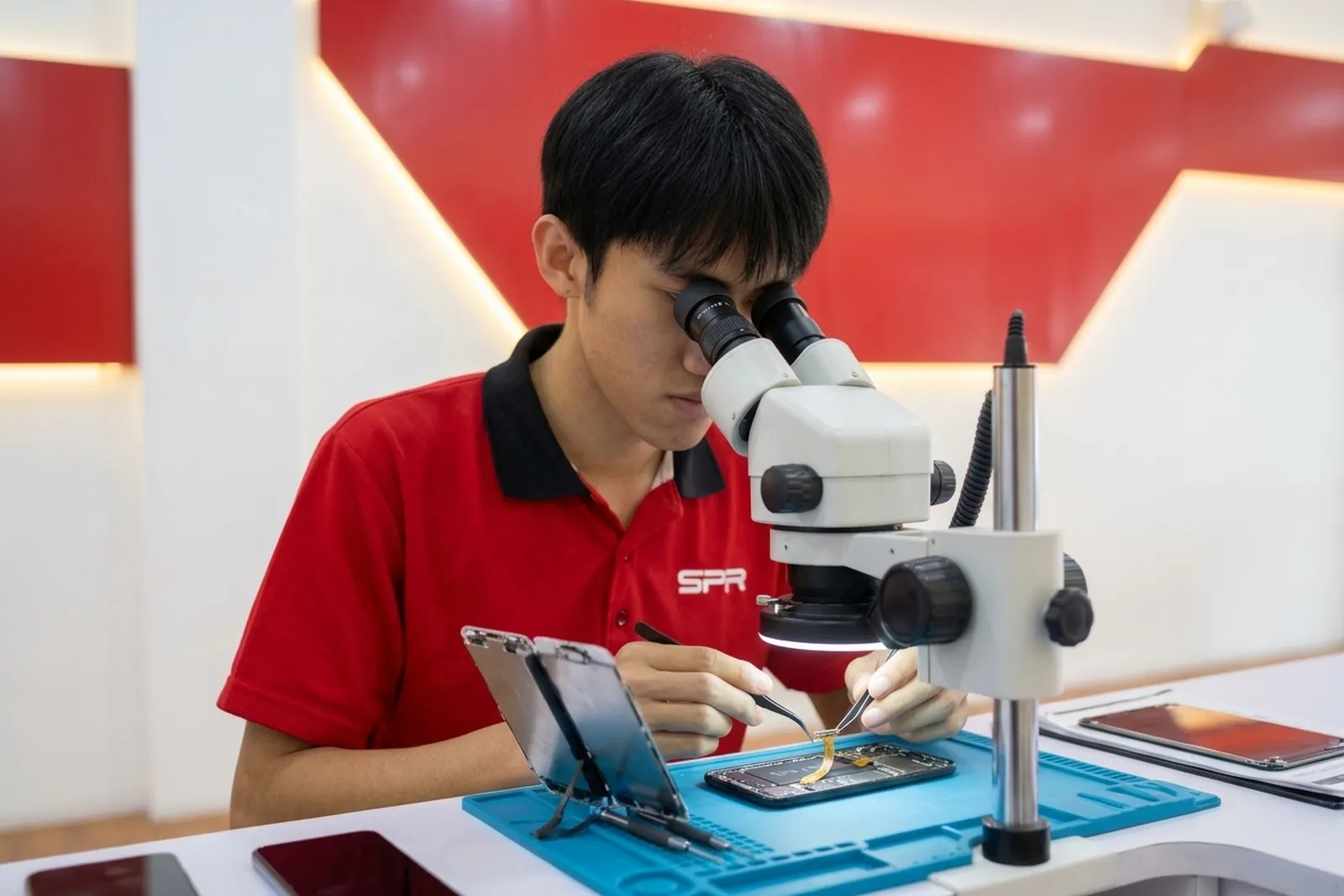 Technician inspecting an iPhone display connector under a microscope